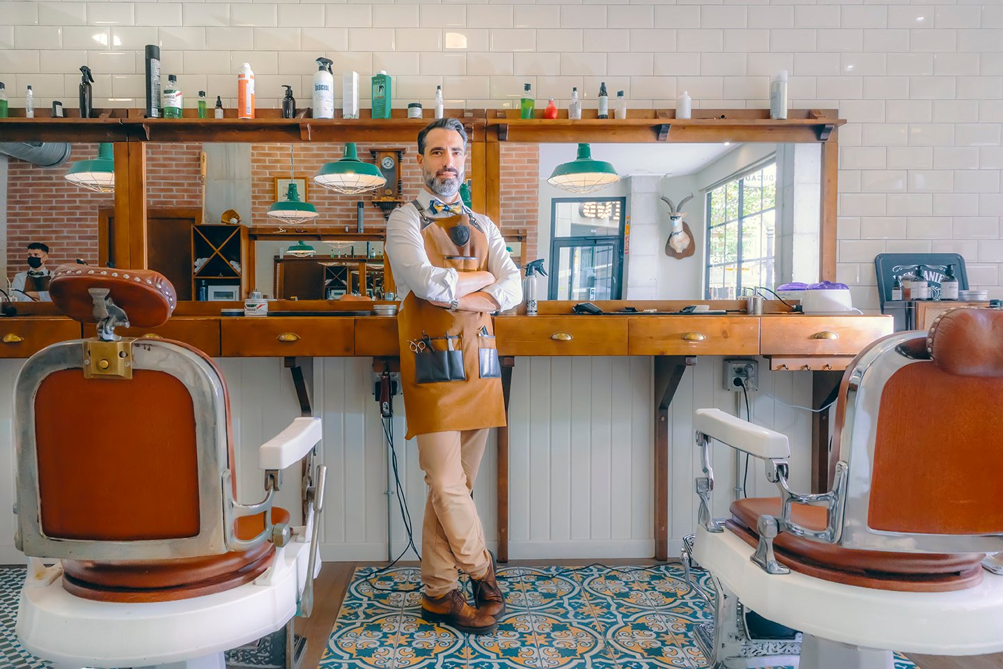 Image d'un barbier posant pour la caméra dans son établissement. Il porte des chaussures Pikolinos.